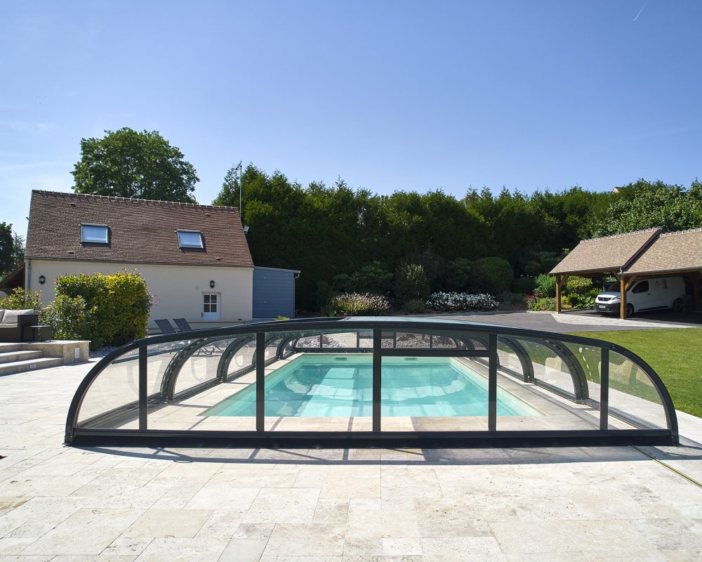 Abri bas EAP motorisé d'une piscine extérieure avec des margelles et plages en travertin