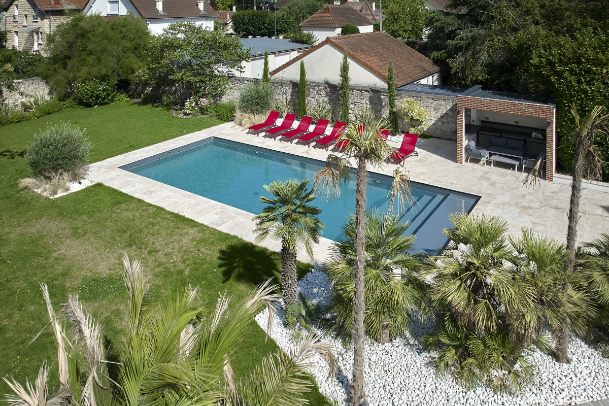 Piscine familiale de 12x5m avec un lien gris anthracite en travertin beige