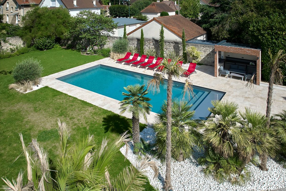 Piscine familiale de 12x5m avec un lien gris anthracite en travertin beige