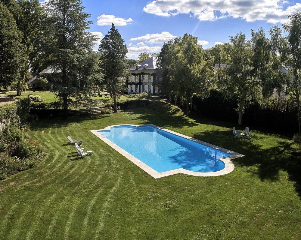 Piscine de 8x20m avec margelles en travertin et liner bleu clair