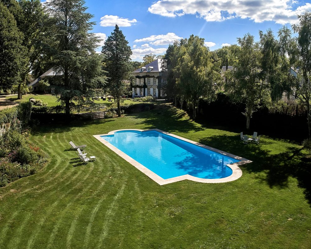 Piscine de 8x20m avec margelles en travertin et liner bleu clair