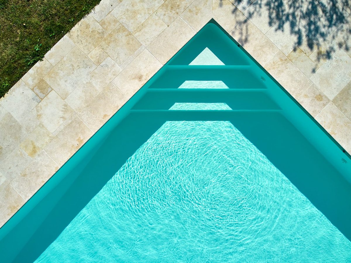 Piscine extérieure en 13x5m avec un escalier d'angle de 3 marches et un liner uni sable