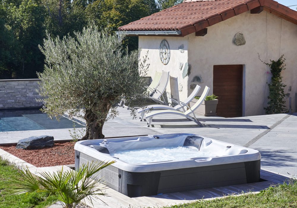 Terrasse avec spa semi-encastré et piscine chauffée, dans un cadre luxueux.