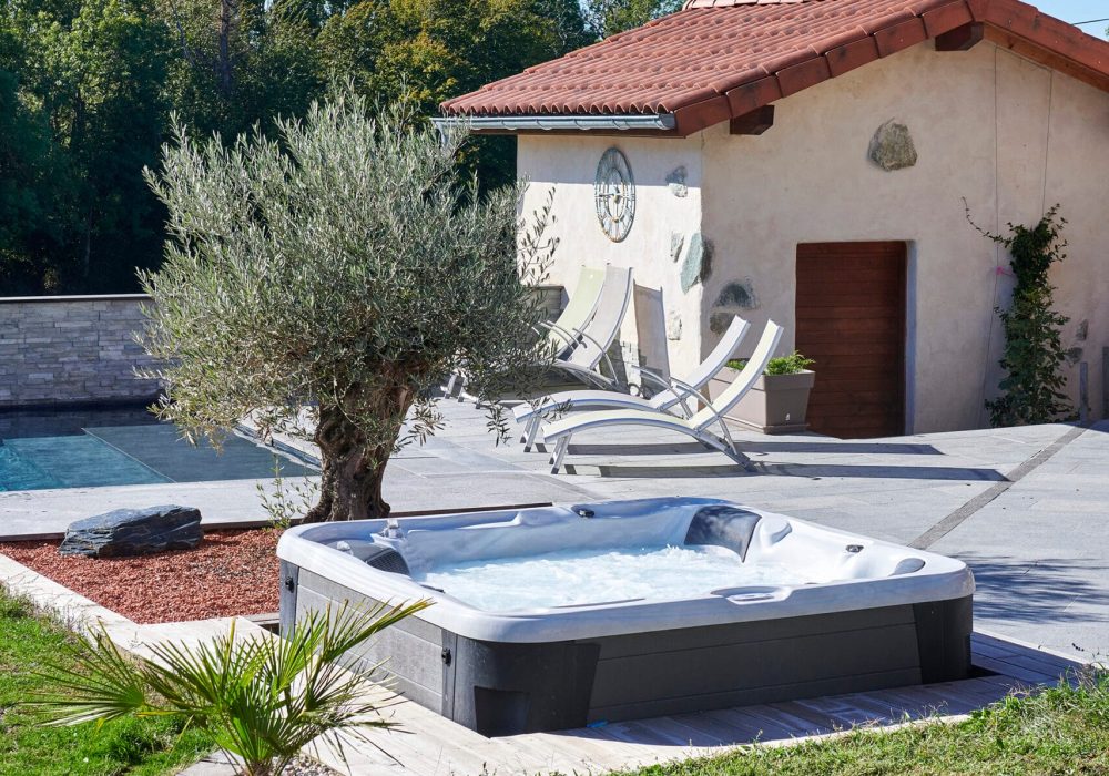 Terrasse avec spa semi-encastré et piscine chauffée, dans un cadre luxueux.