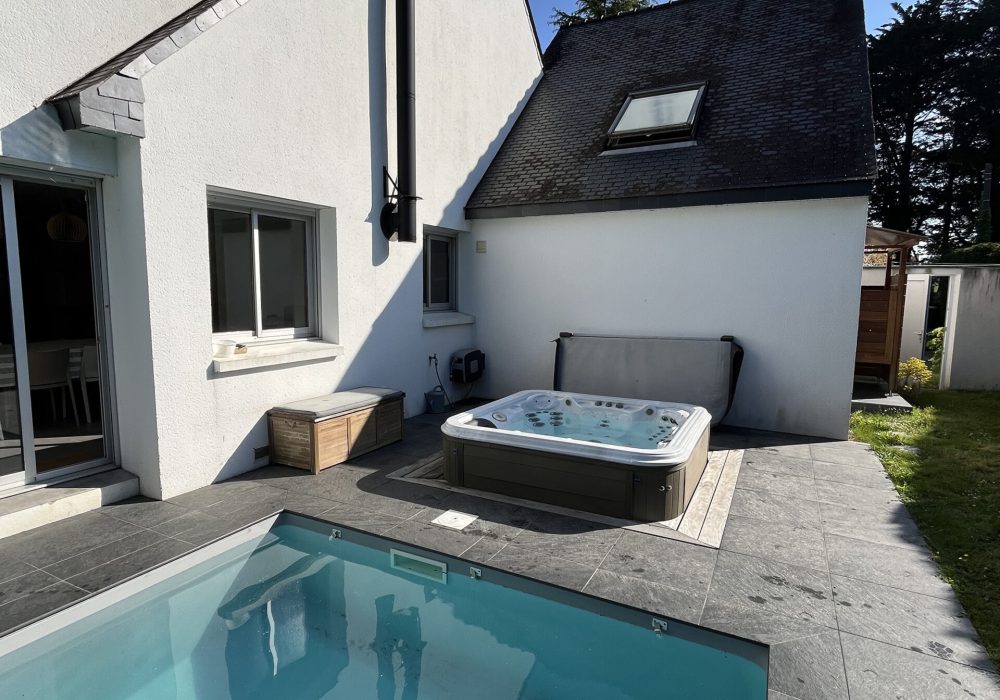 Spa semi encastré aux abords d'une piscine extérieure.