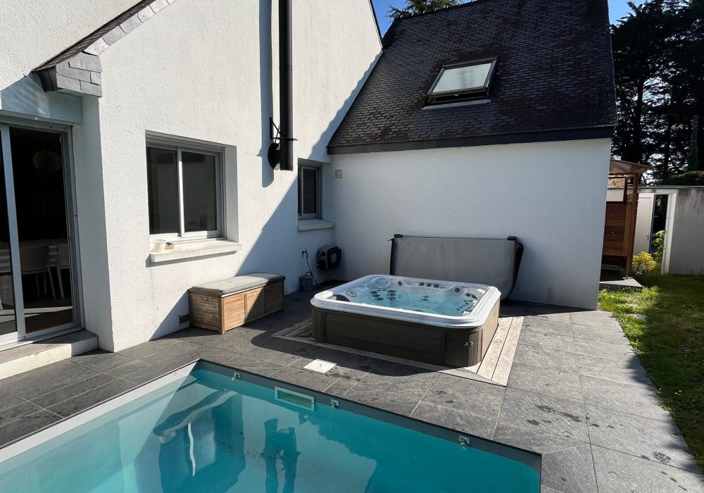 Spa semi encastré aux abords d'une piscine extérieure.